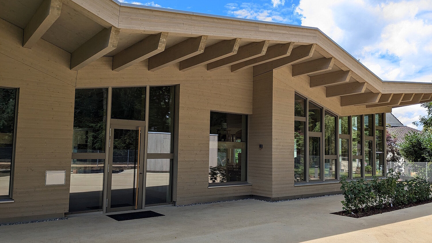 Kindergartenfassade mit grossen Holzfenstern und Türen